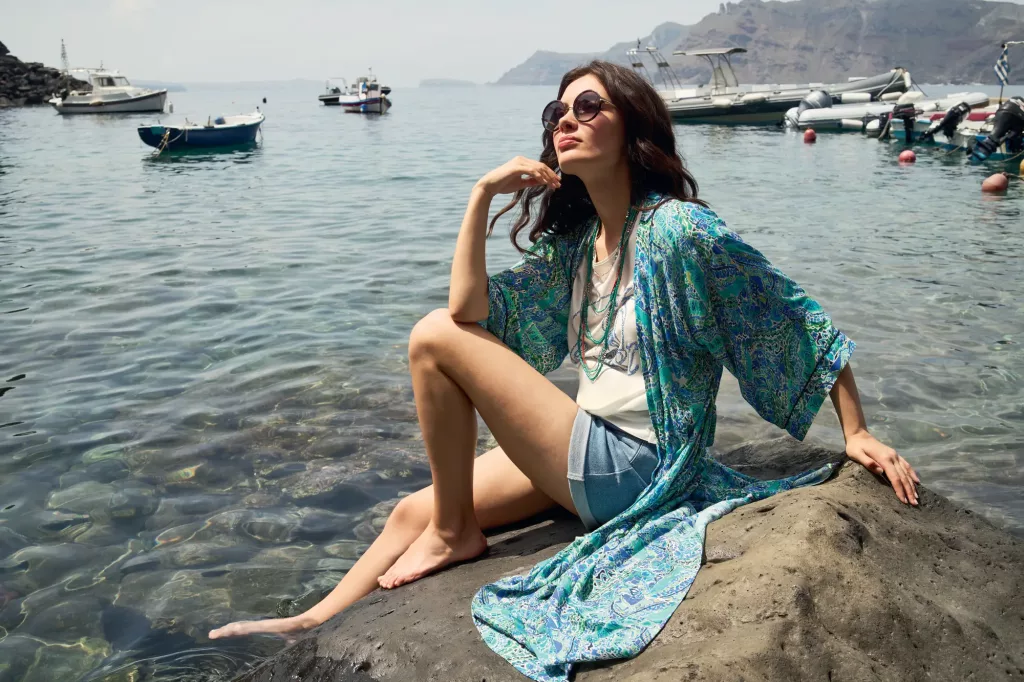 Photo d'un femme au bord de l'eau assise sur un rocher