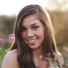 Photo d'un femme avec des fleurs en arrière plan et un couché de soleil